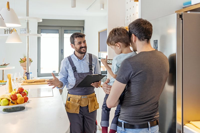 Male HVAC technician going over possible DIY AC maintenance tasks with homeowner who is holding thier child.