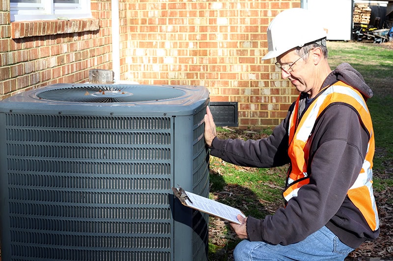 Home inspection of central air unit by a maintenance worker
