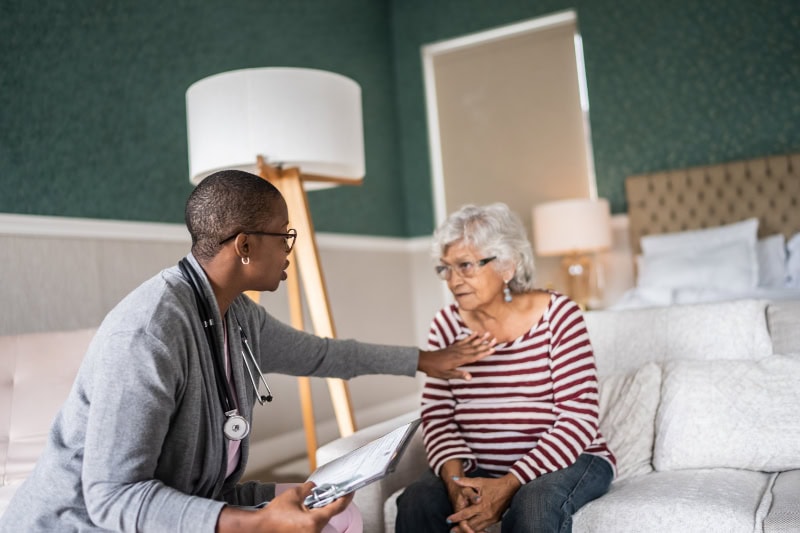 A healthcare professional, speaking with an elderly woman.
