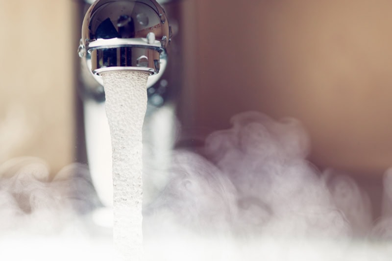 3 Signs That It’s Time to Replace Your Water Heater. Close up photo of hot steamy water coming out of a faucet.